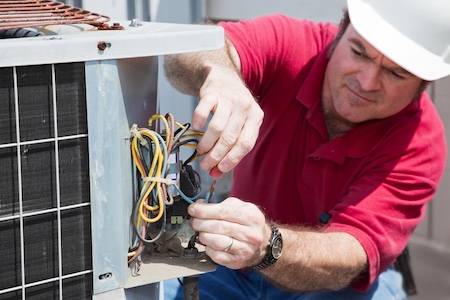 Technician repairing an outdoor AC condenser at a Roachdale, Indiana home